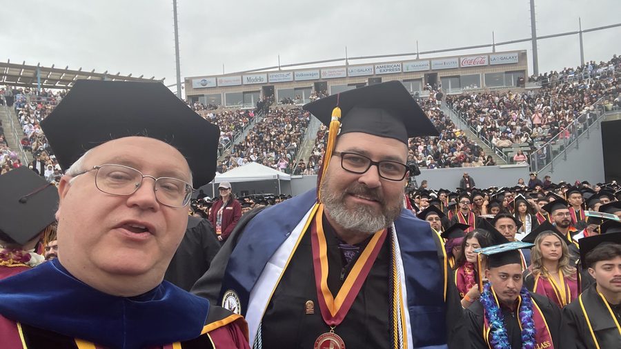 Thomas Norman with a graduate wearing a veteran's stole and honors medal at commencement