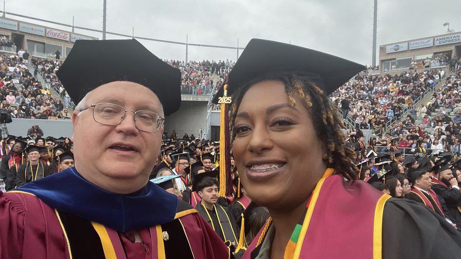 Thomas Norman in doctoral regalia with a graduate at commencement 2025